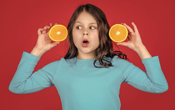 shocked teen kid hold orange fruit on purple background. - Фото, зображення