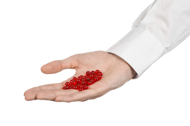 Medical theme: doctor's hand holding a red capsule for health on a white background isolated - Zdjęcie, obraz