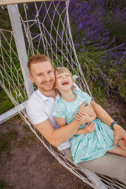Onnellinen isä ja tytär makaavat riippumatossa. laventelikenttä taustalla - Valokuva, kuva