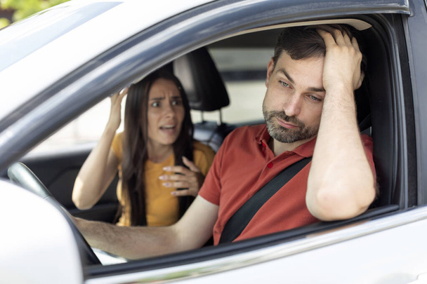 Emotional millennial caucasian couple having conflict in car, woman shouting at bored distracted man, sitting in automobile. Unhappy spouses in auto arguing about road, have conflict - Photo, image