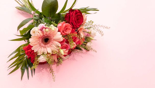 Echt Schöne frische Blumenstrauß auf rosa Hintergrund. Bunte gemischte Rosen, Nelkenschabe, grüne Blätter, Gerber. Horizontale Ebene, Kopierraum für Text. - Foto, Bild