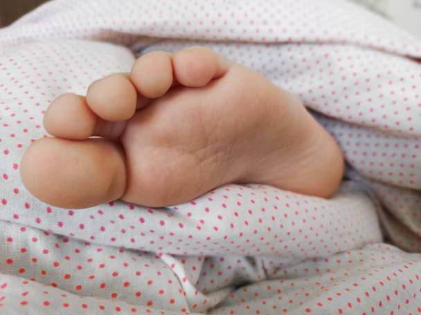 Primer plano del pie del bebé en la cama. Vista de cerca del pie de un bebé caucásico mientras duerme en su cama. - Foto, imagen