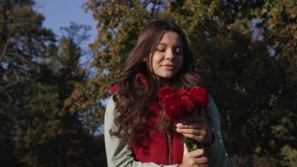 teen girl with autumn flowers outside. slow motion of teen girl with autumn flowers. teen girl with autumn flowers outdoor. teen girl with autumn flowers bouquet. - Footage, Video