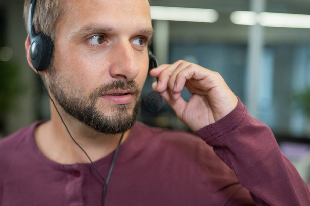 Kaukázusi szakállas férfi fülhallgatóval. Férfi call center munkavállaló. - Fotó, kép