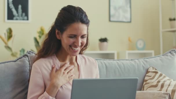 Vrolijke jonge blanke vrouw zwaaien en glimlachen op laptop terwijl het hebben van online video gesprek met een vriend van thuis - Video