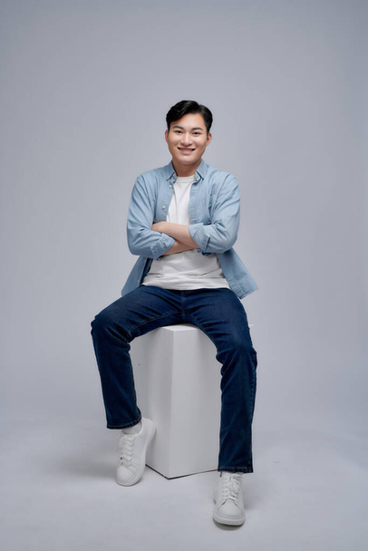 Young Asian man sitting on background - Фото, изображение