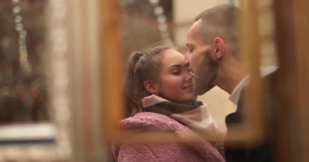 Közelkép egy fiatal szerelmespár arcáról, akik csókolóznak és ölelkeznek az utcán egy borús őszi napon.. - Felvétel, videó