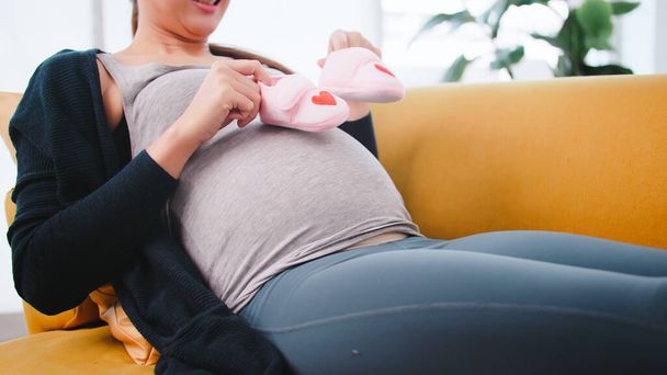 mooi aziatische zwanger vrouw is voorbereiding kleding voor haar pasgeboren baby. - Foto, afbeelding