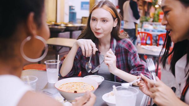 Többnemzetiségű női barátok egy csoportja utcai ételeket fogyaszt a Yaowarat úton vagy a kínai negyedben Bangkokban, Thaiföldön.. - Fotó, kép