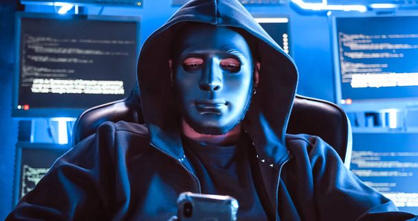 Un hacker che indossa una maschera per coprirsi il viso sta usando il computer per hackerare i dati per ottenere il riscatto dalle vittime. - Foto, immagini
