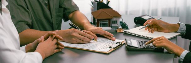 Panorama view of married couple signing house loan contract with real estate agent. Client customer purchasing new home, sealing the deal with signatures after reviewing terms and agreements. Prodigy - Photo, Image