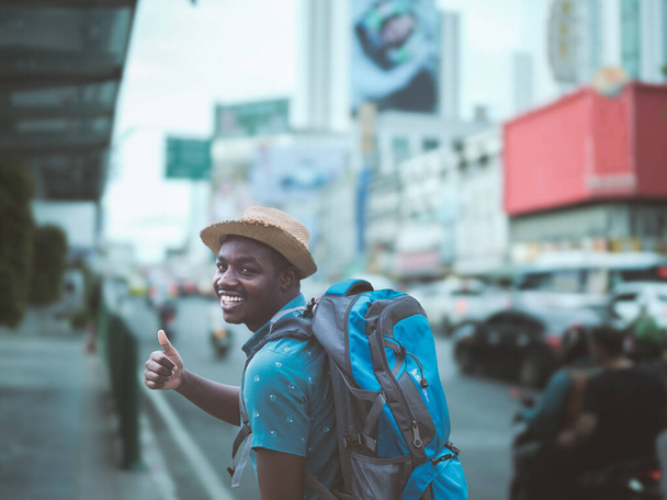 African tourists with backpacks walking in the downtown area of Bangkok, Thailand. - Photo, Image