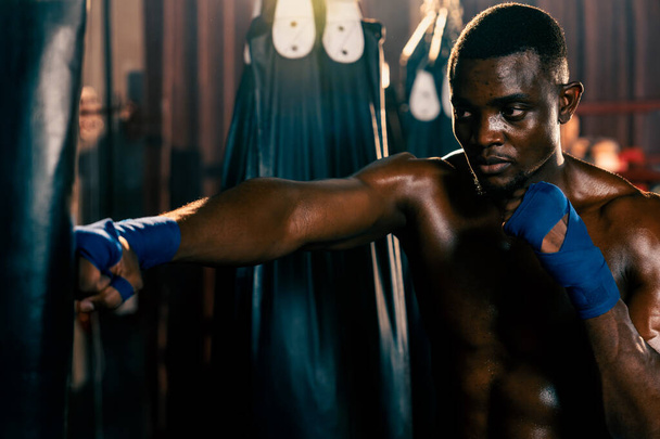 Sac de boxe afro-américain noir comme équipement d'entraînement de sac de boxe dans la salle de gym pour l'entraînement de force et d'endurance pour un match de boxe professionnel. Impulsion - Photo, image
