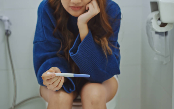 Mulher estressada sentada no banheiro e esperando pelos resultados do teste de gravidez. - Foto, Imagem