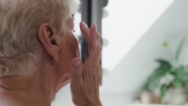 Oudere vrouw die een oogcrème gaat aanbrengen. Opgenomen met RED helium camera in 8K.  - Video