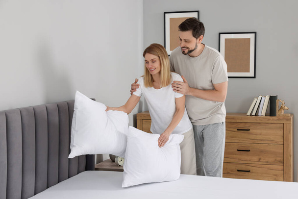 Couple putting pillows on bed at home. Domestic chores - Fotoğraf, Görsel