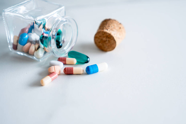 Медицина або вітамінні таблетки вийшли з пляшки або ложки на фоні білої підлоги. - Фото, зображення