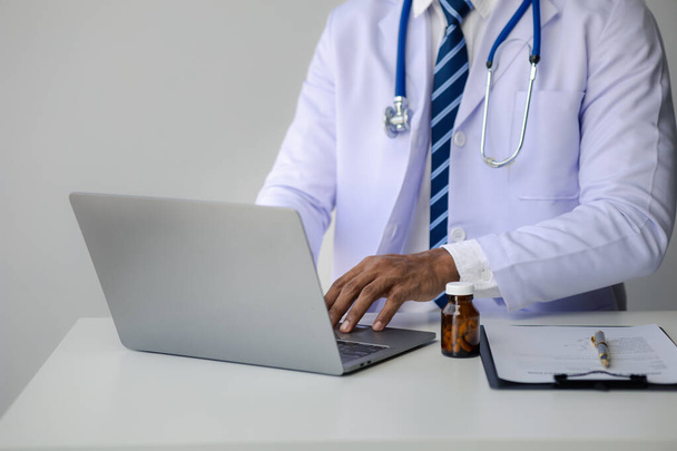 Doctor is typing on laptop keyboard, filling out patient's visit for medical records, treating disease with tinnitus, doctor examining a patient. Doctor concept and treatment by medical professionals. - Photo, Image