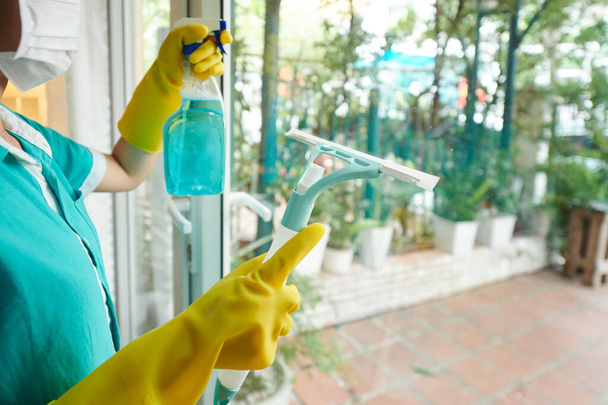 Ammattimainen siivouspalvelu työntekijä suojakäsineissä puhdistus lasiovi spray ja kaavin - Valokuva, kuva