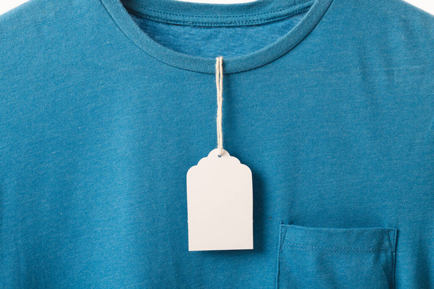Blue t shirt with tag and copy space on white background. Fashion, clothes, colour and fabric concept. - Фото, зображення