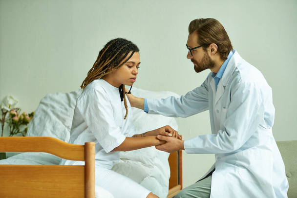male doctor holding hands of african american woman, comforting patient, private ward, hospital - Photo, Image