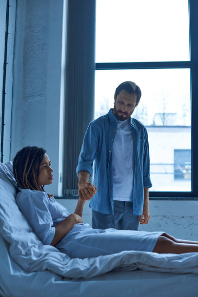 conceito de aborto espontâneo, homem triste segurando a mão da esposa afro-americana, tristeza, cama de hospital enfermaria privada - Foto, Imagem