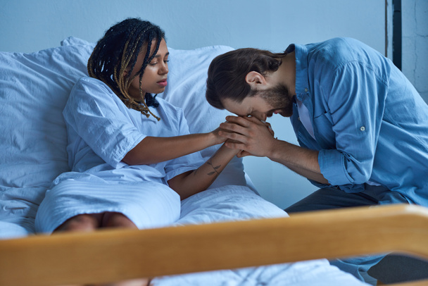 Концепция выкидыша, грустная африканская американка, держащая за руку скорбящего мужа, больничную палату - Фото, изображение
