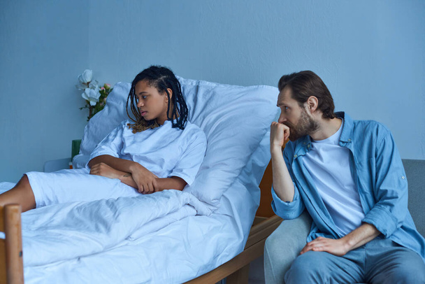 man grieving near depressed african american wife, hospital ward, miscarriage concept, despair - Foto, afbeelding