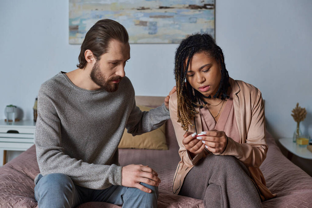 bearded man calming down african american girlfriend with pregnancy test, unexpected news, shock - Photo, Image