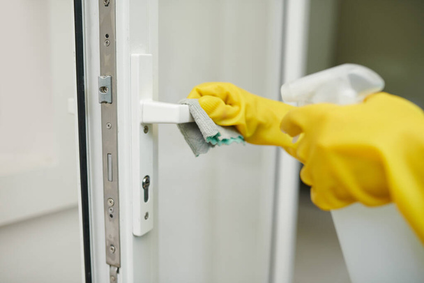 Mãos em luvas de silicone desinfetando o punho da porta de alto toque com detergente spray - Foto, Imagem