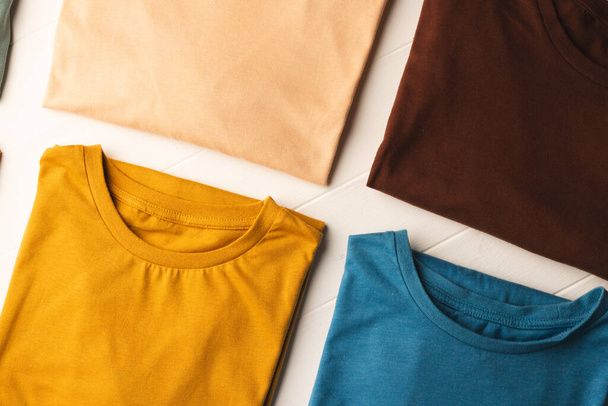Close up of flat lay of multi coloured t shirts and copy space on white boards background. Fashion, clothes, colour and fabric concept. - Φωτογραφία, εικόνα