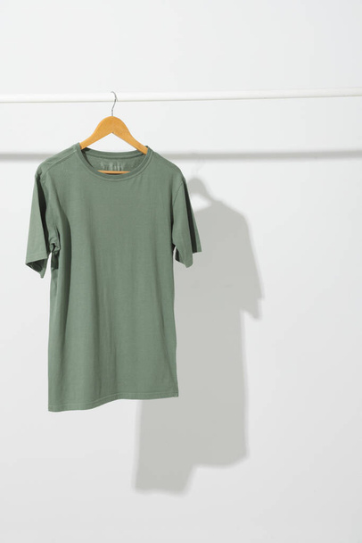Green t shirt on hanger hanging from clothes rail with copy space on white background. Fashion, clothes, colour and fabric concept. - Fotoğraf, Görsel