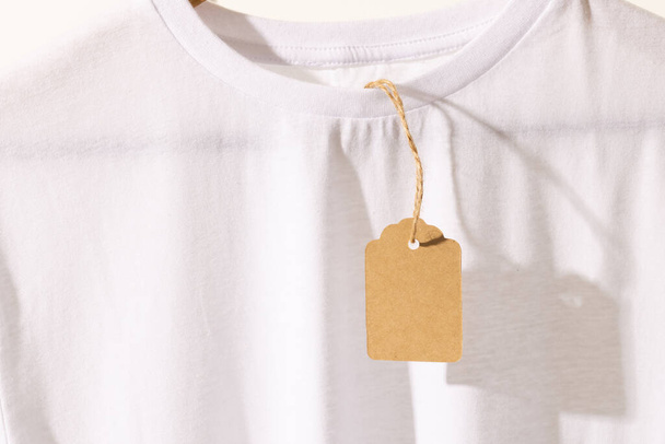 White t shirt with tag with copy space on white background. Fashion, clothes, colour and fabric concept. - Фото, зображення