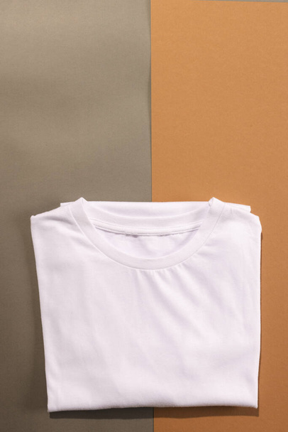Close up of folded white t shirts and copy space on brown background. Fashion, clothes, colour and fabric concept. - Foto, Bild
