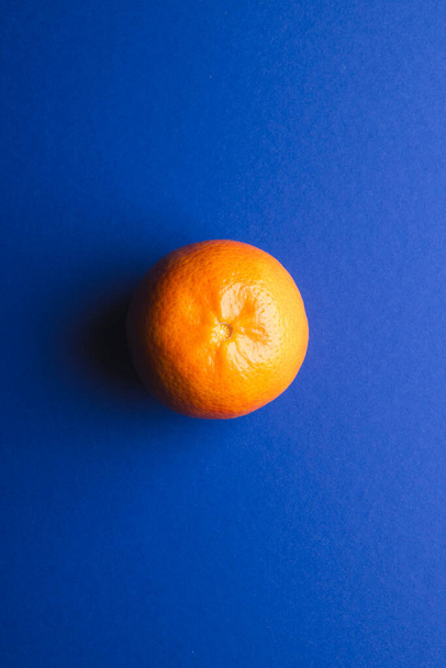 Zavřít mandarinky a kopírovat prostor na modrém pozadí. Ovoce, exotické ovoce, potraviny, čerstvost a barevný koncept. - Fotografie, Obrázek