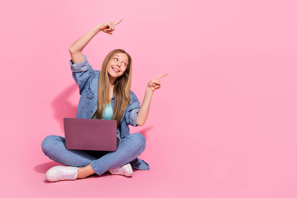 Photo of attractive positive stylish girl sit floor raise hand demonstrate empty space sale discount isolated on pink color background. - Foto, Imagen