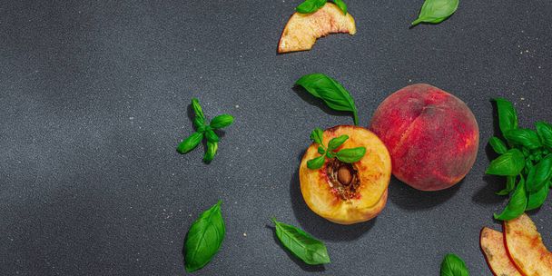 Γευστικό φόντο φρούτων. Ροδάκινα ώριμα και φρέσκα φύλλα βασιλικού. Σύγχρονη σκληρό φως, σκοτεινή σκιά, επίπεδη lay, μορφή λάβαρο - Φωτογραφία, εικόνα