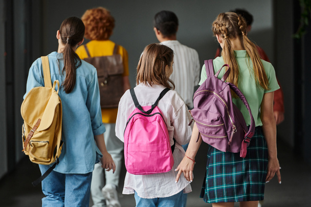 vista trasera de los escolares caminando en el pasillo de la escuela entre clases, estudiantes adolescentes, de vuelta a la escuela - Foto, imagen