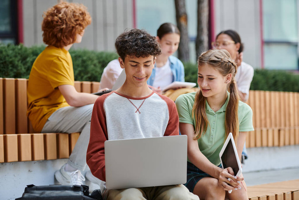 επιστροφή στο σχολείο, χαρούμενο αγόρι και κορίτσι χρησιμοποιώντας gadgets κοντά στο σχολείο, έφηβους μαθητές σε εξωτερικούς χώρους, e-study - Φωτογραφία, εικόνα