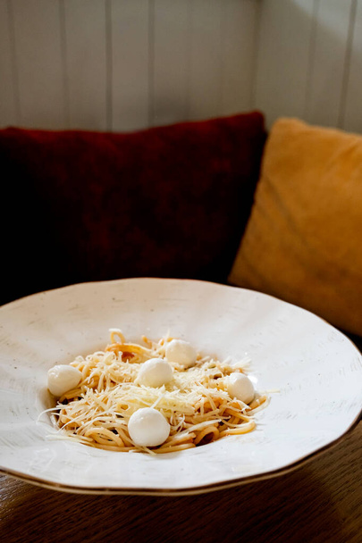 вкусная вегетарианская спагетти-макароны с мозареллой и томатным соусом на деревянном столе в кафе - Фото, изображение