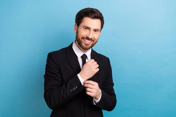 Portrait of fashionable handsome young businessman model fixing his buttoning cufflinks jacket shirt isolated on blue color background. - Foto, Imagem