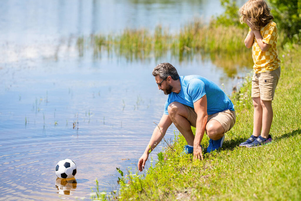 Father and son enjoy a friendly game of football. happy childhood of son playing with father. father and son summer activity. son has bonding time with father outdoor. Outdoor playtime. - Fotoğraf, Görsel