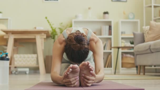 Mujer joven caucásica respirando profundamente mientras hace ejercicios de estiramiento en la esterilla de yoga en casa - Imágenes, Vídeo