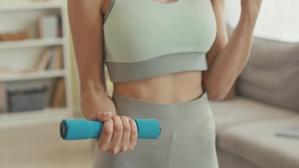 Cropped shot of unrecognizable fit woman in tight sportswear lifting dumbbells at home - Footage, Video