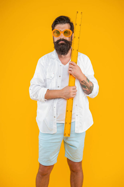 man hold measuring ruler isolated on yellow. man hold measuring ruler in studio. man hold measuring ruler on background. photo of man hold measuring ruler. - Fotó, kép