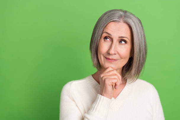 Photo of retired woman grey hair wear trendy white shirt touch chin thoughts look empty space brainstorming isolated on green background. - Fotó, kép