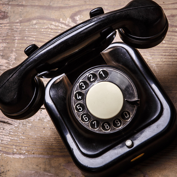 Старий чорний телефон з пилом і подряпинами на дерев'яній підлозі
 - Фото, зображення