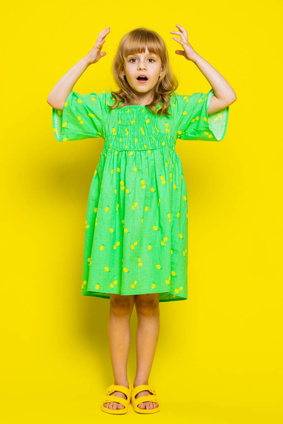 Excited amazed child girl kid looking shocked surprised wow showing hands brain head explosion gesture. Little preteen children touching her head and showing explosion on yellow background. Vertical - Photo, Image