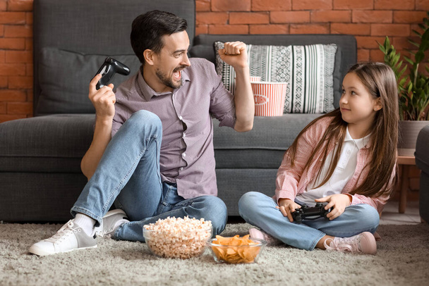 Padre con su pequeña hija jugando videojuegos en casa - Foto, Imagen