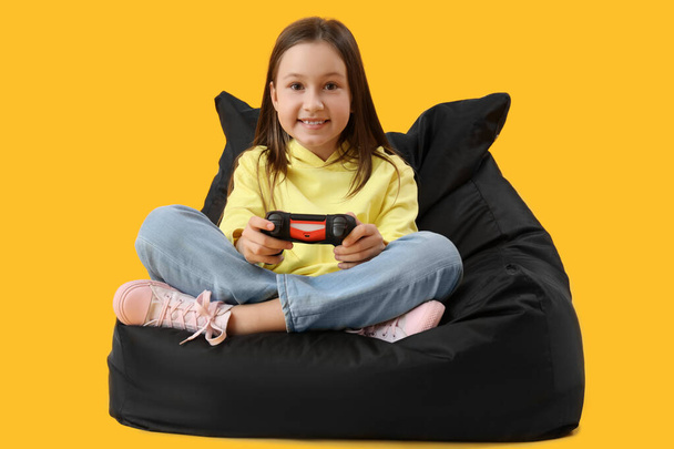 pieni tyttö pelaa videopeliä keltaisella taustalla - Valokuva, kuva